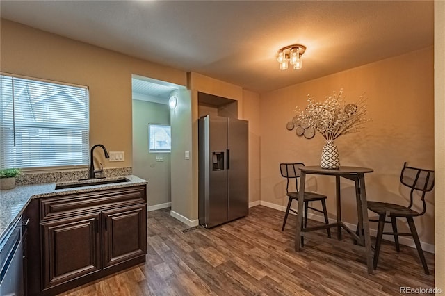 kitchen with dark brown cabinets, appliances with stainless steel finishes, sink, light stone countertops, and dark hardwood / wood-style floors