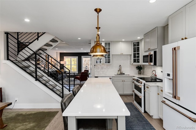 kitchen featuring sink, range with two ovens, white fridge with ice dispenser, dark hardwood / wood-style floors, and hanging light fixtures