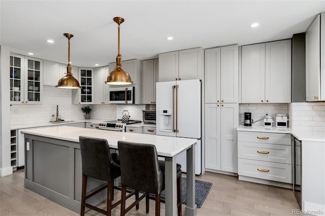 kitchen with gray cabinetry, white appliances, decorative backsplash, light wood-type flooring, and a kitchen island