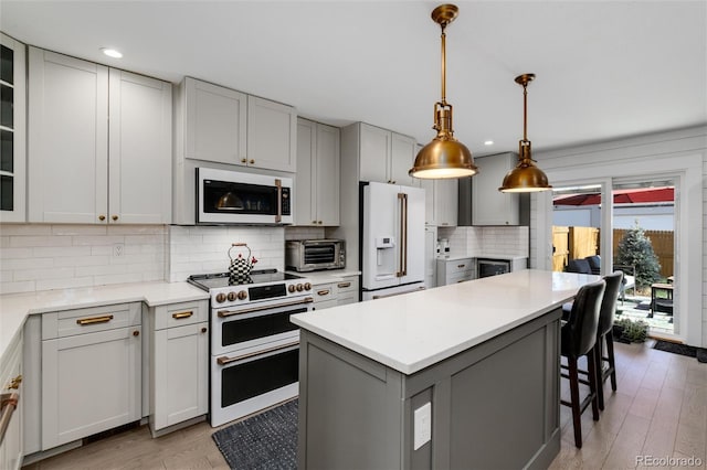 kitchen featuring gray cabinets, light wood-type flooring, white appliances, and backsplash