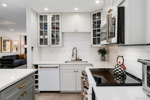 kitchen featuring decorative backsplash, stainless steel appliances, sink, light hardwood / wood-style flooring, and white cabinets