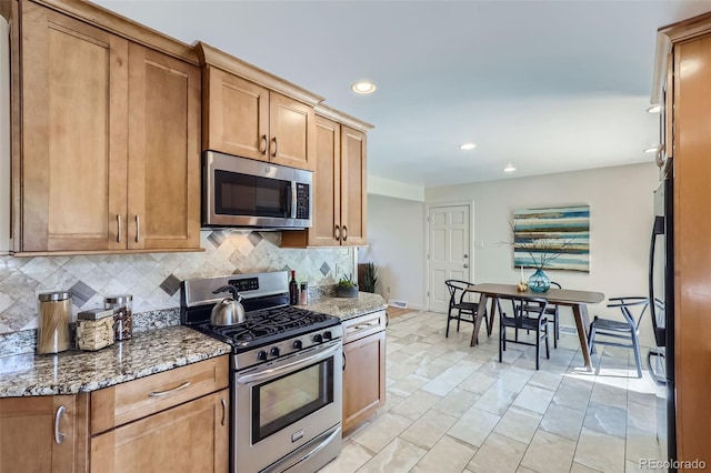 kitchen with appliances with stainless steel finishes, decorative backsplash, and dark stone counters