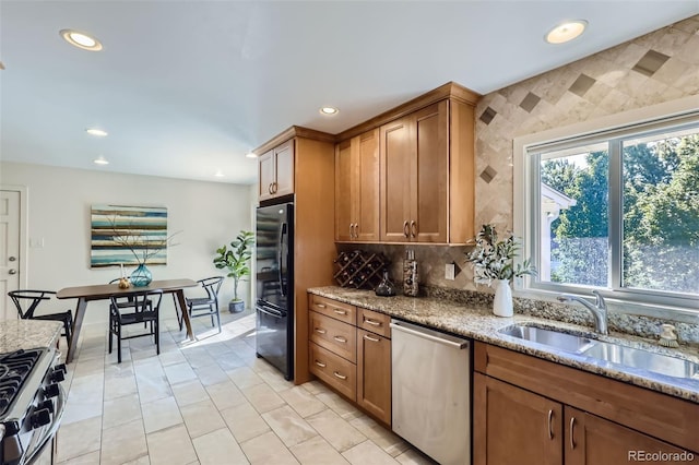 kitchen with light stone counters, stainless steel appliances, sink, and a wealth of natural light