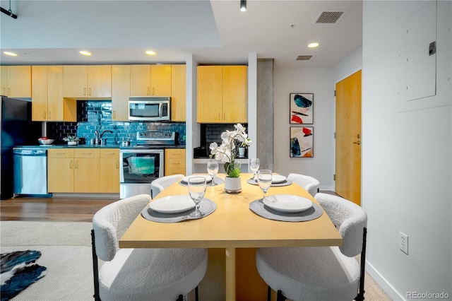 1700 Bassett St Unit 1119, Denver, CO 80202 - kitchen featuring appliances with stainless steel finishes, light brown cabinetry, electric panel, tasteful backsplash, and a sink