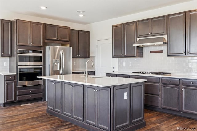 6214 Long Branch Dr, Parker, CO 80134 - kitchen featuring dark wood-style flooring, under cabinet range hood, light countertops, appliances with stainless steel finishes, and decorative backsplash