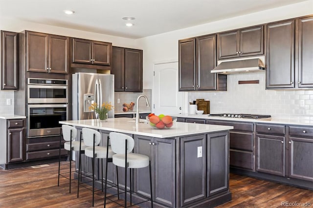 6214 Long Branch Dr, Parker, CO 80134 - kitchen featuring under cabinet range hood, decorative backsplash, dark wood-style floors, and appliances with stainless steel finishes