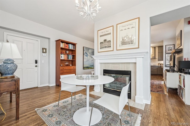 dining area featuring a notable chandelier, wood-type flooring, and a tile fireplace