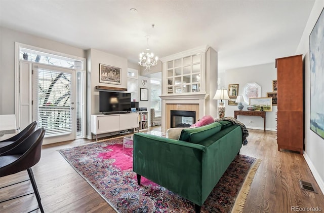 living room featuring a chandelier, a fireplace, and light hardwood / wood-style flooring