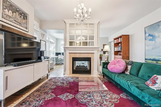 living room with hardwood / wood-style flooring, a tile fireplace, and a chandelier