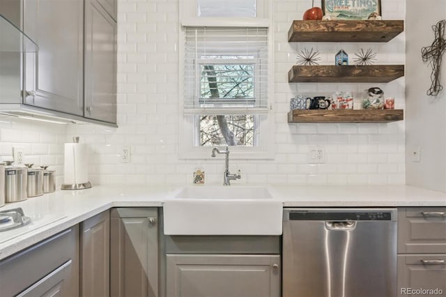 kitchen featuring sink, gray cabinetry, tasteful backsplash, stainless steel dishwasher, and light stone countertops