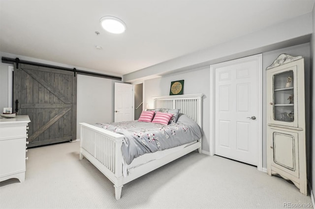 bedroom featuring light carpet and a barn door