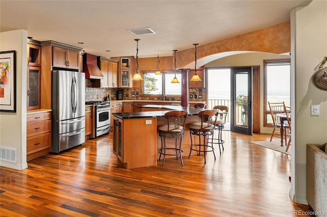 8932 Eastridge Rd, Golden, CO 80403 - kitchen with stainless steel appliances, wall chimney exhaust hood, arched walkways, and dark wood-type flooring