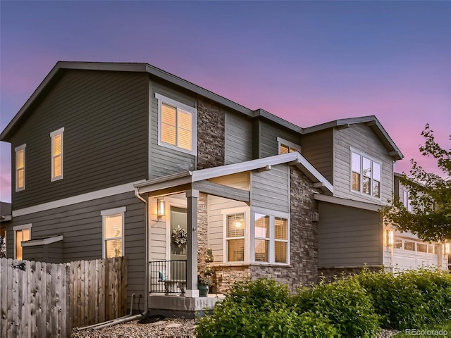 exterior space with stone siding, a garage, and fence