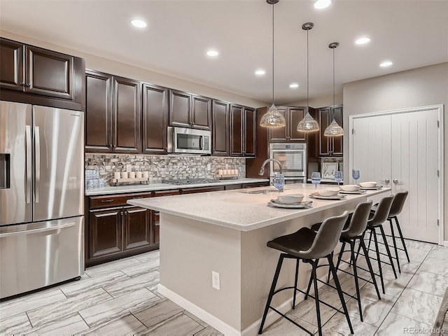 kitchen with tasteful backsplash, pendant lighting, light stone counters, a kitchen breakfast bar, and stainless steel appliances