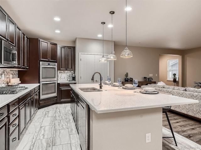 kitchen featuring stainless steel appliances, a sink, a kitchen breakfast bar, marble finish floor, and backsplash