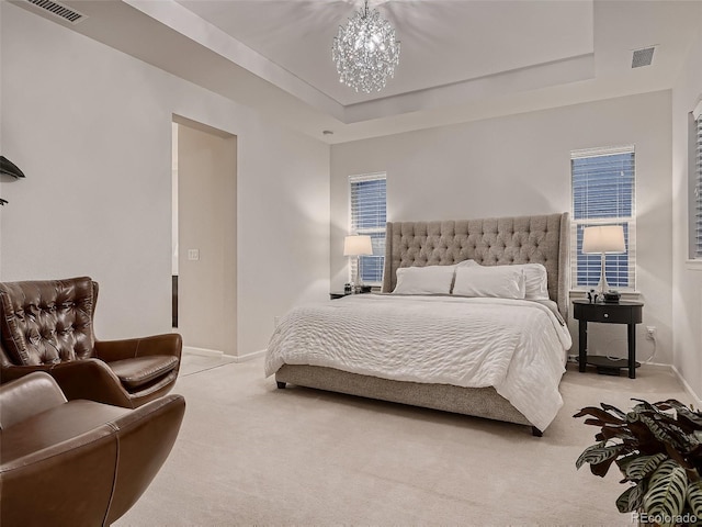 bedroom with light carpet, visible vents, a tray ceiling, and a notable chandelier