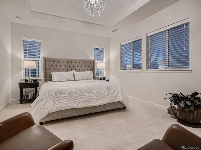 carpeted bedroom with an inviting chandelier, a raised ceiling, baseboards, and visible vents