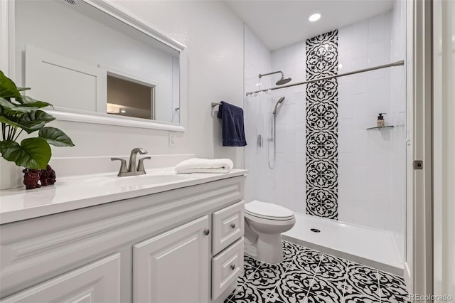 bathroom featuring toilet, recessed lighting, tiled shower, tile patterned floors, and vanity