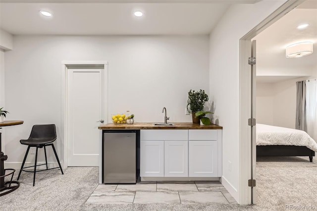 bar featuring recessed lighting, wet bar, freestanding refrigerator, and a sink