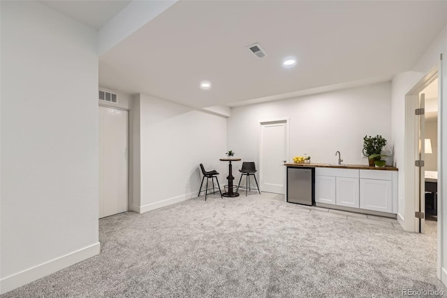 interior space with fridge, indoor wet bar, visible vents, and carpet flooring