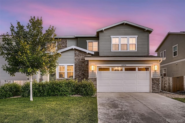 traditional-style home with driveway, stone siding, fence, a yard, and an attached garage