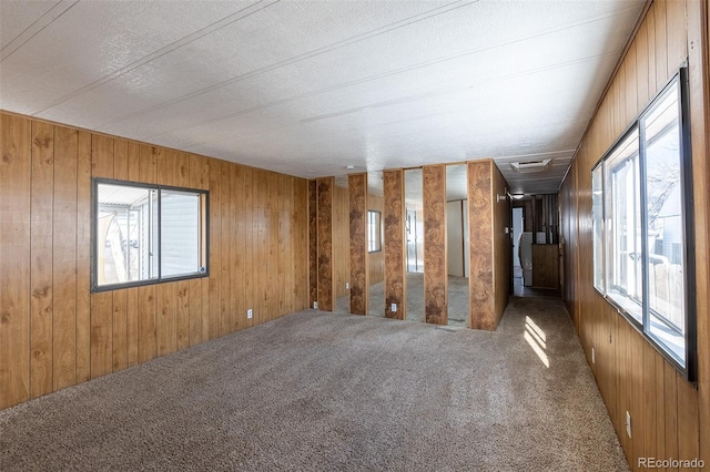 spare room with wood walls, carpet, and visible vents