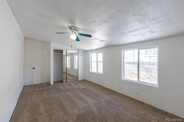 unfurnished bedroom with a closet, carpet flooring, ceiling fan, and a textured ceiling