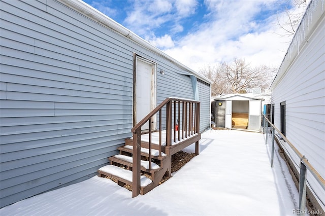 snow covered deck featuring an outdoor structure, a storage shed, and fence