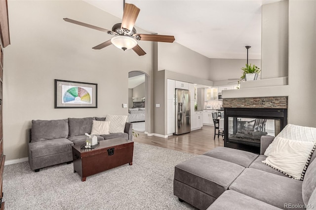 392 Driftwood Cir, Lafayette, CO 80026 - living room featuring arched walkways, a ceiling fan, a multi sided fireplace, vaulted ceiling, and light carpet