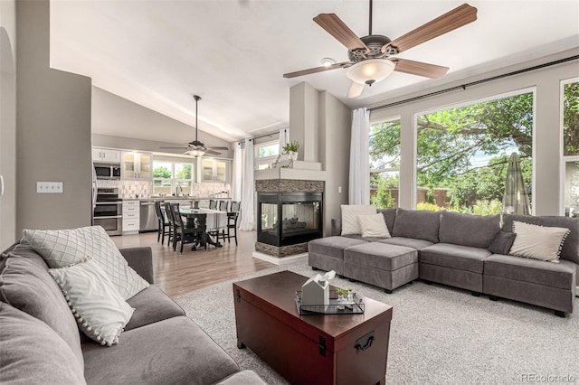 392 Driftwood Cir, Lafayette, CO 80026 - living area with a ceiling fan, a multi sided fireplace, vaulted ceiling, and light wood-style flooring