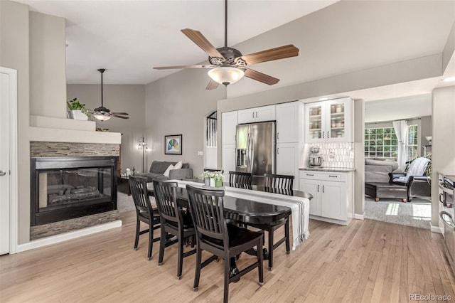 392 Driftwood Cir, Lafayette, CO 80026 - dining space with a ceiling fan, light wood-style flooring, a stone fireplace, and high vaulted ceiling