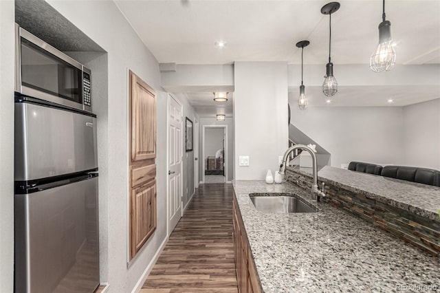 392 Driftwood Cir, Lafayette, CO 80026 - kitchen featuring appliances with stainless steel finishes, dark wood finished floors, light stone countertops, pendant lighting, and open floor plan