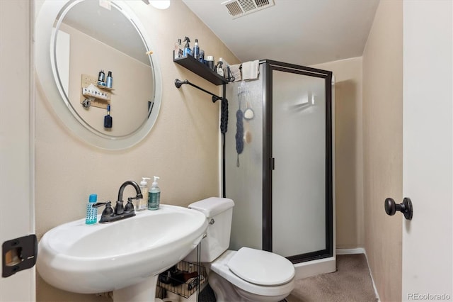 bathroom with a shower with shower door, sink, and toilet