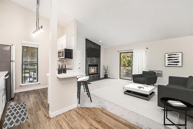 living room featuring light hardwood / wood-style floors, high vaulted ceiling, a large fireplace, and heating unit