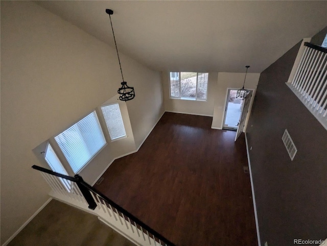 unfurnished living room with dark hardwood / wood-style flooring and an inviting chandelier