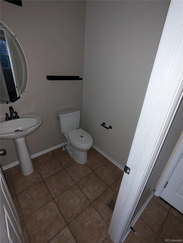 bathroom with toilet, tile patterned floors, and sink