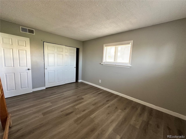 10211 Ura Ln Unit 7-108, Thornton, CO 80260 - unfurnished bedroom with baseboards, dark wood-style flooring, a closet, and a textured ceiling