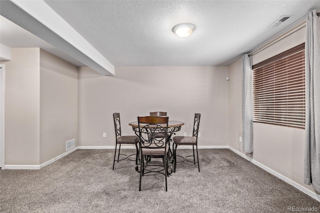 dining area featuring carpet flooring, a textured ceiling, and baseboards