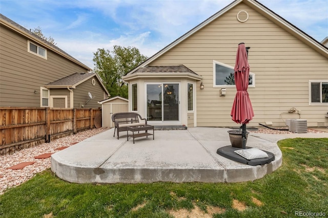 rear view of property featuring a patio area, a fenced backyard, a shed, an outbuilding, and cooling unit