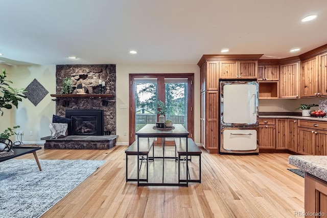 26732 Main St, Conifer, CO 80433 - kitchen with fridge, light wood finished floors, a stone fireplace, recessed lighting, and brown cabinets