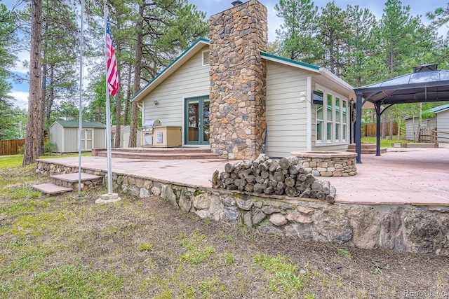 26732 Main St, Conifer, CO 80433 - back of house with french doors, a patio area, a storage unit, a gazebo, and a chimney