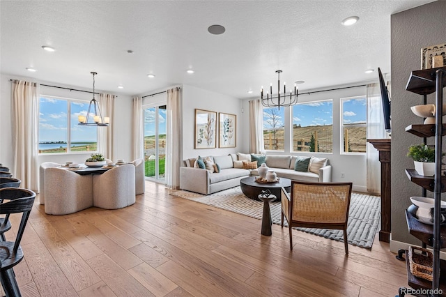 living room with light hardwood / wood-style flooring, a textured ceiling, and an inviting chandelier