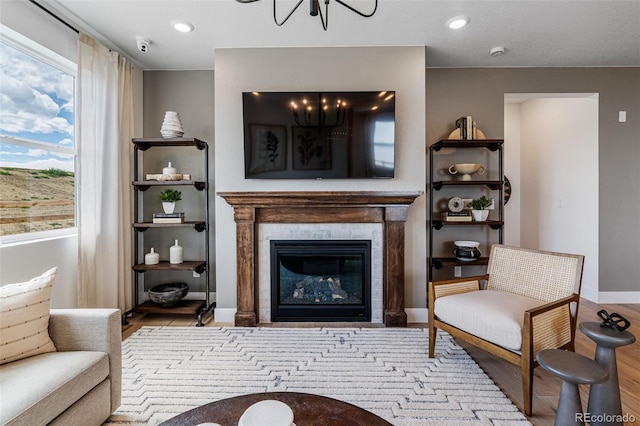 living area with a tiled fireplace, light hardwood / wood-style floors, and a notable chandelier