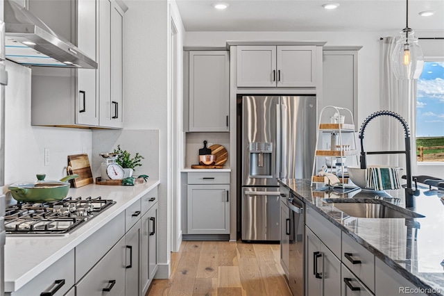 kitchen featuring appliances with stainless steel finishes, gray cabinets, range hood, and light hardwood / wood-style flooring