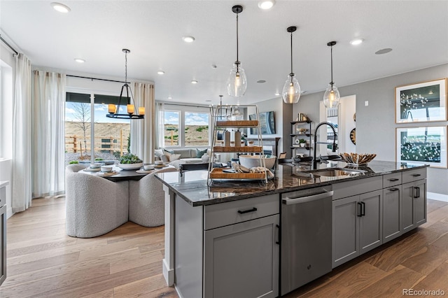 kitchen with gray cabinetry, dishwasher, sink, light wood-type flooring, and an island with sink