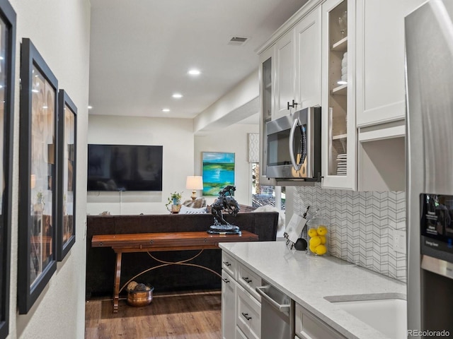 6405 Warriors Run, Littleton, CO 80125 - kitchen with stainless steel appliances, open floor plan, glass insert cabinets, backsplash, and white cabinetry