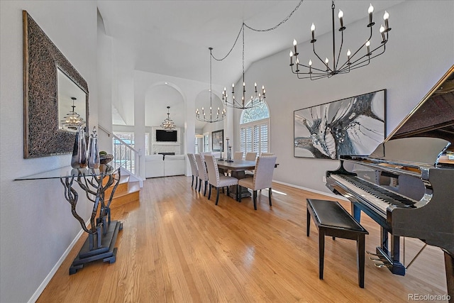 dining space featuring a notable chandelier, a towering ceiling, baseboards, and wood finished floors