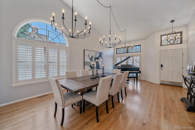 dining space with light wood-style floors, high vaulted ceiling, and an inviting chandelier