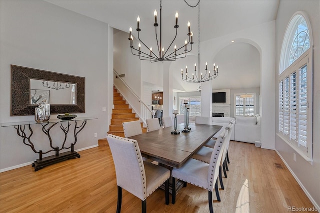 dining space featuring a chandelier, stairs, light wood-style flooring, and a high ceiling