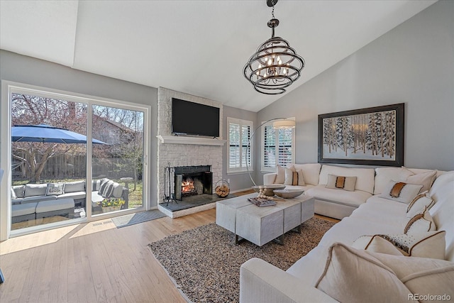 living room with a fireplace, a notable chandelier, wood finished floors, and a healthy amount of sunlight
